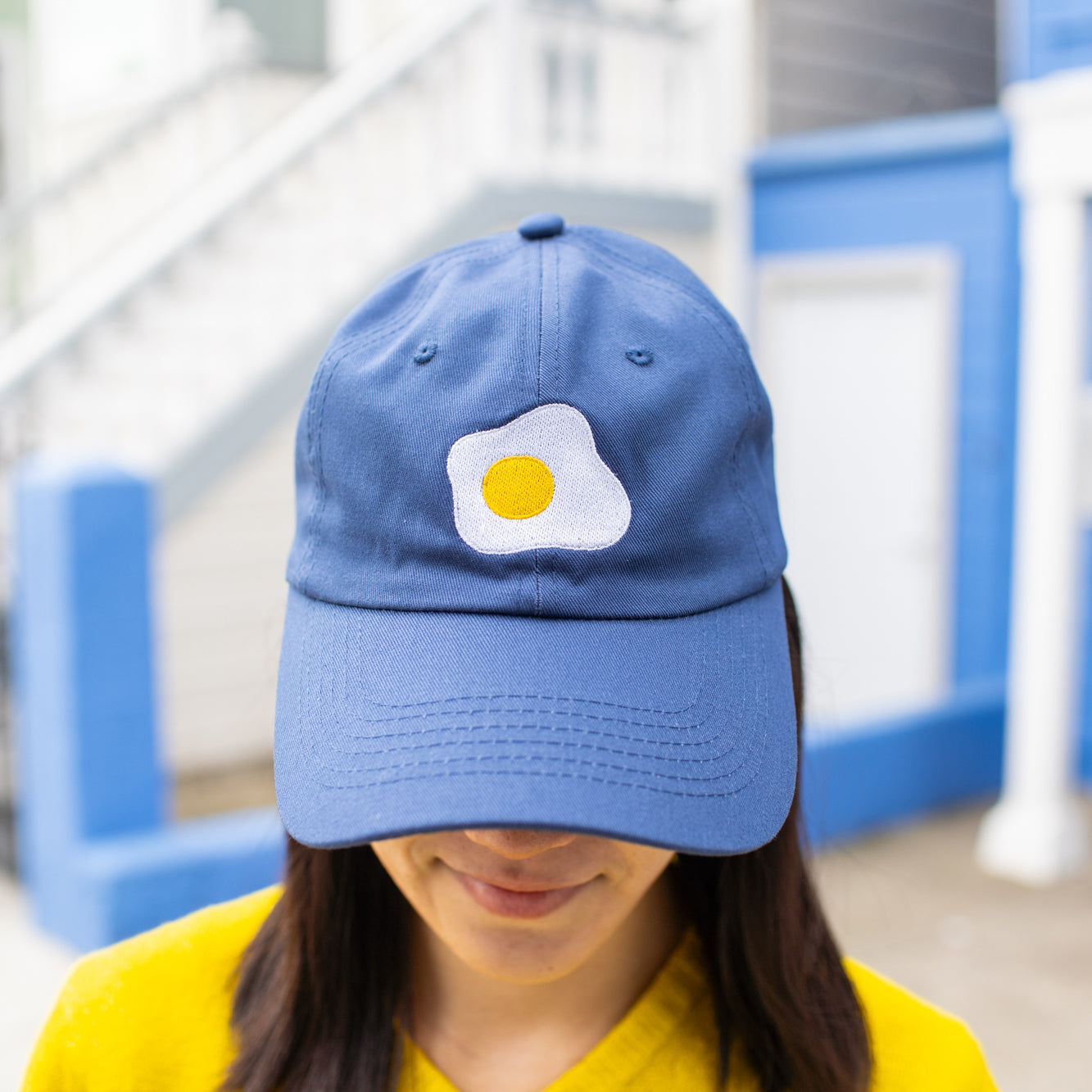 Close-up of navy blue baseball cap with fried sunny side up egg embroidered on front