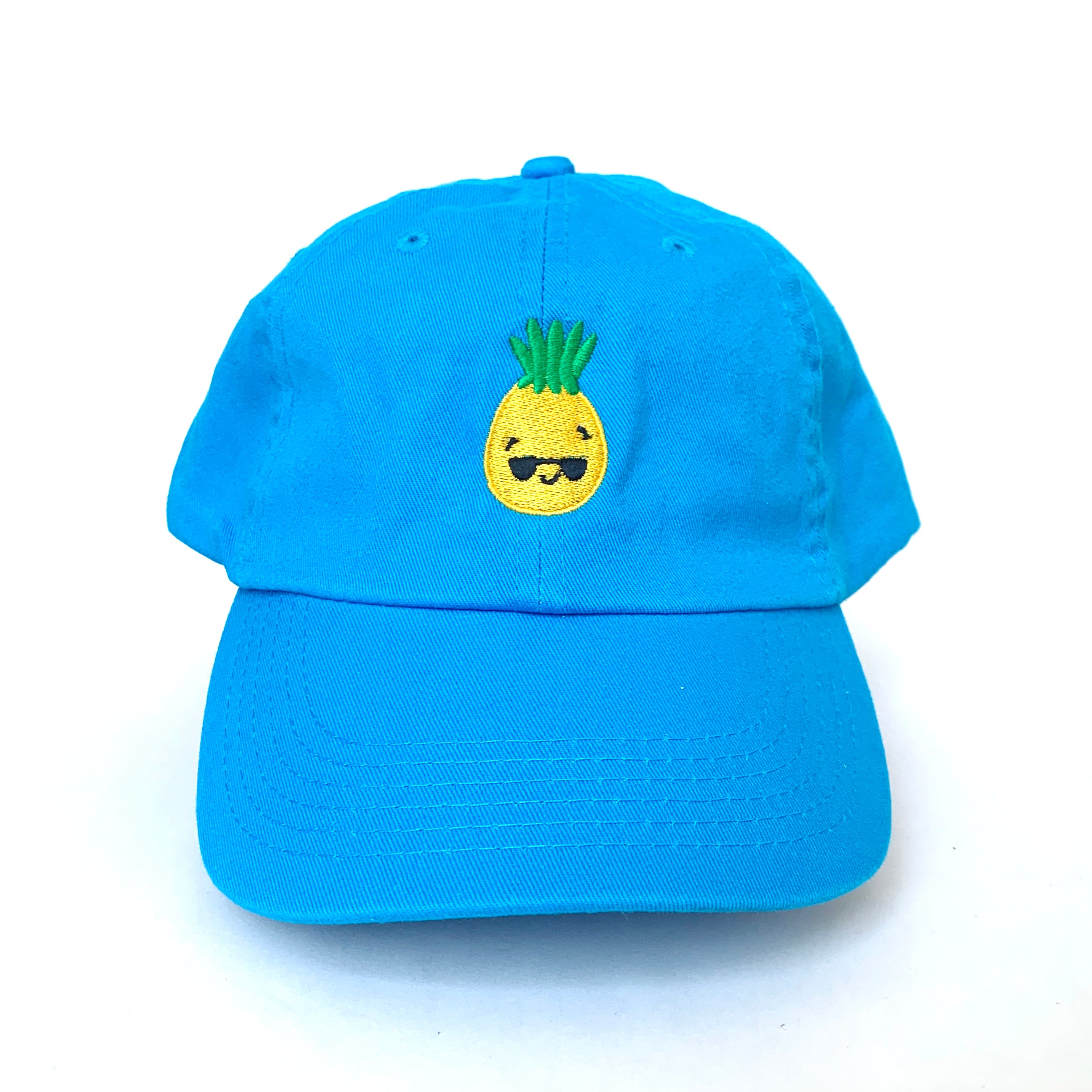 Bright blue baseball cap with pineapple wearing sunglasses embroidered on the front.