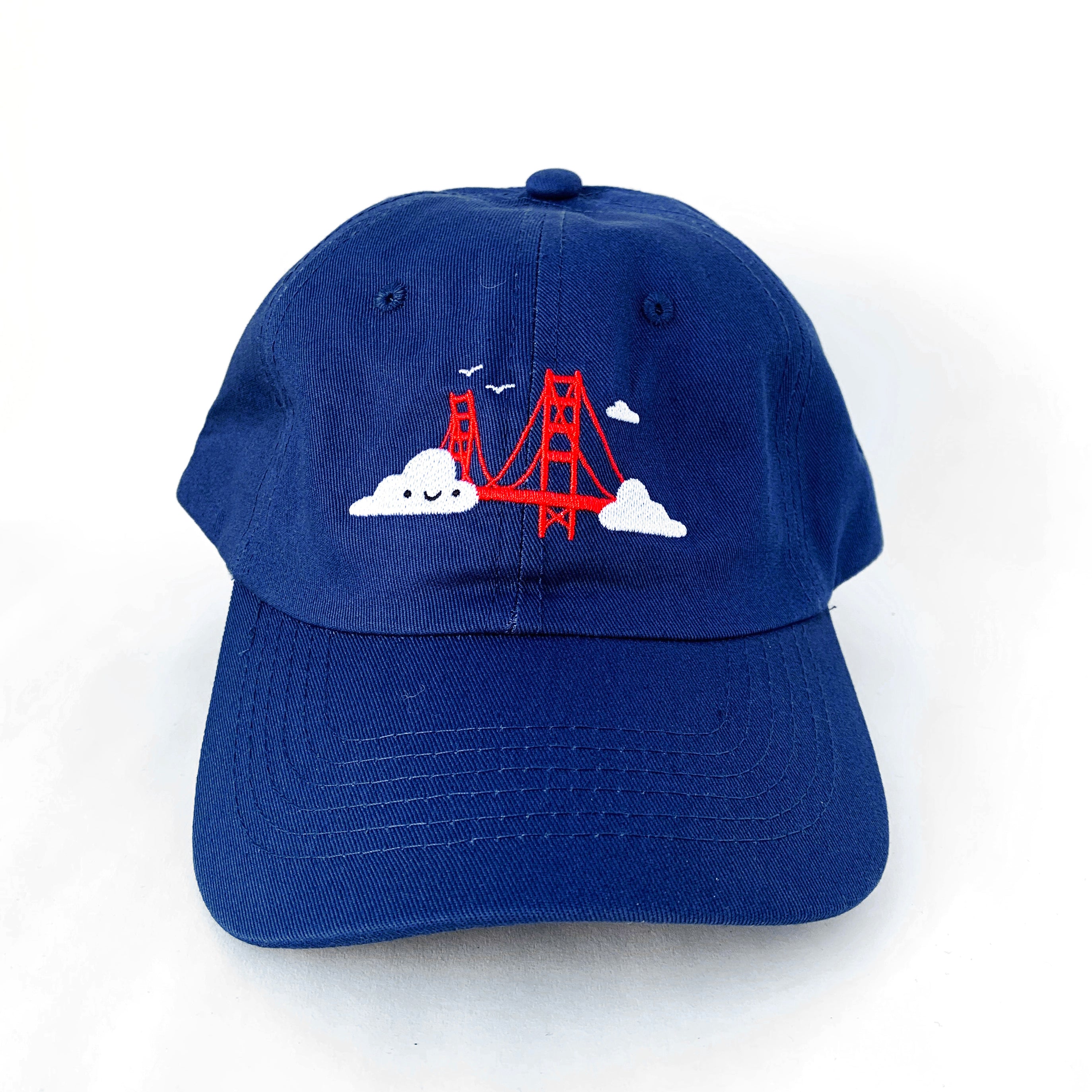 Navy blue baseball cap with Golden Gate Bridge and smiling clouds embroidery.