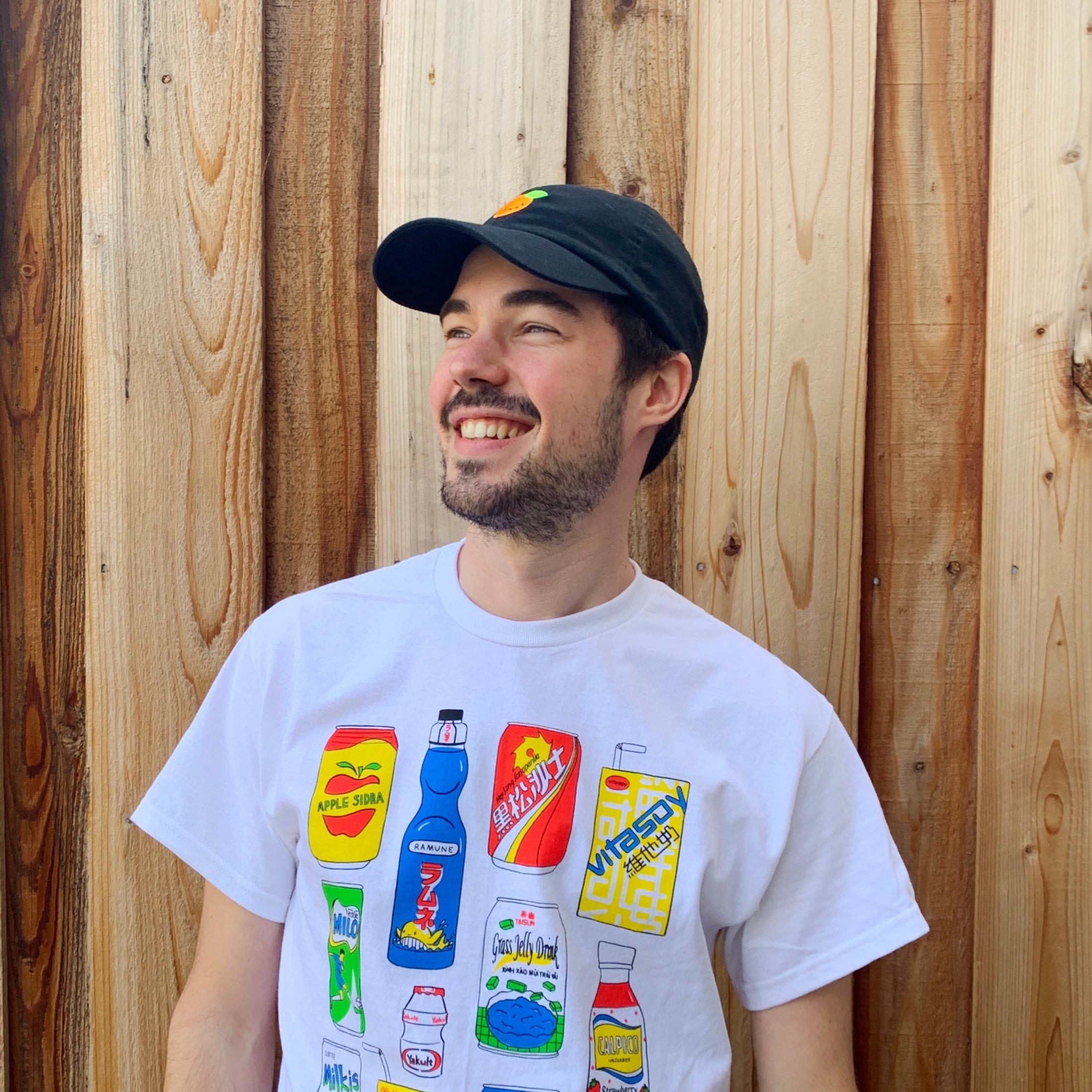 Person smiling in a white t-shirt wearing a black baseball cap.