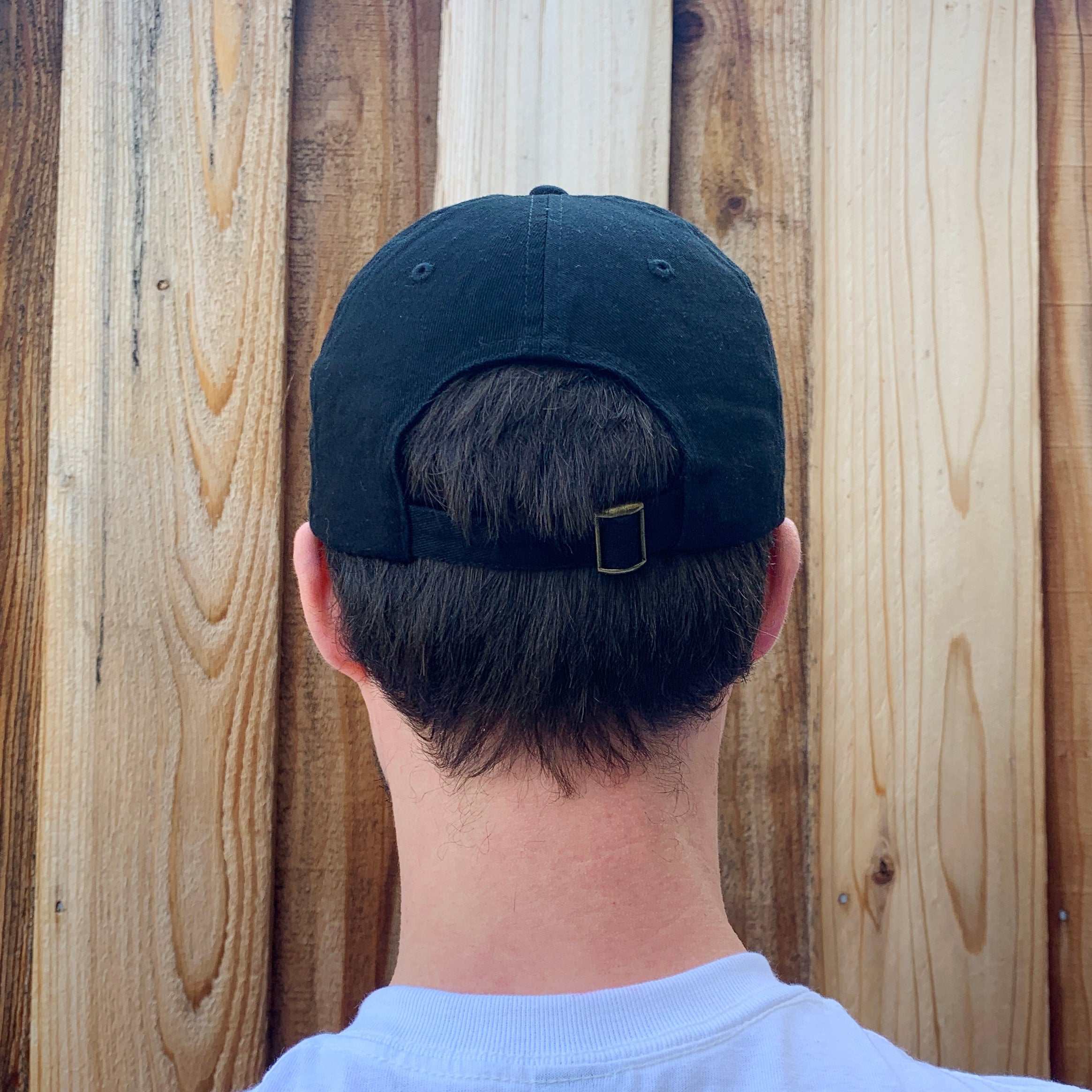 Back view of black baseball cap with adjustable buckle.