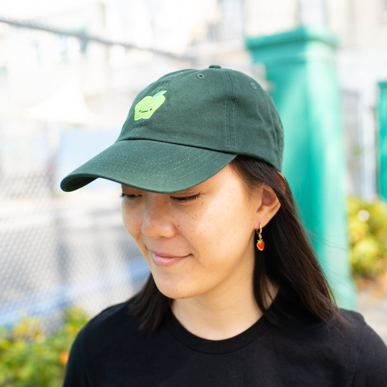 Person smiling wearing green baseball cap with light green apple  with a straight face embroidered on front