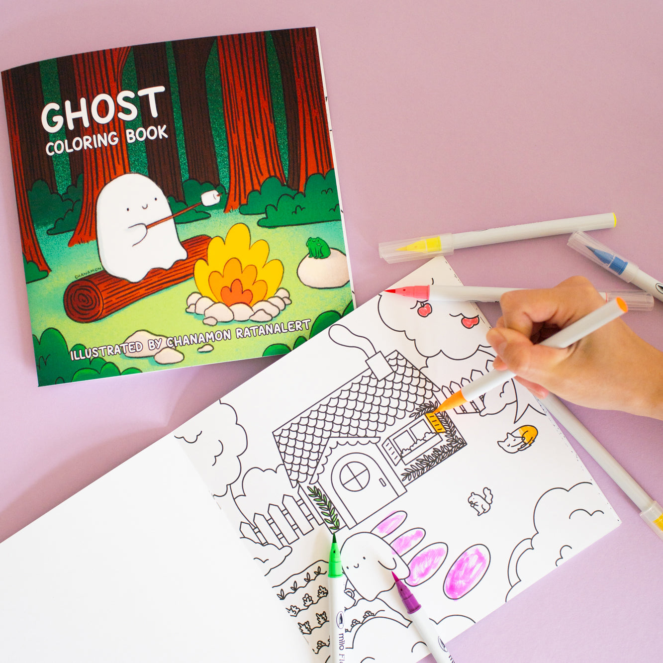 A hand coloring the first page of a coloring book with markers