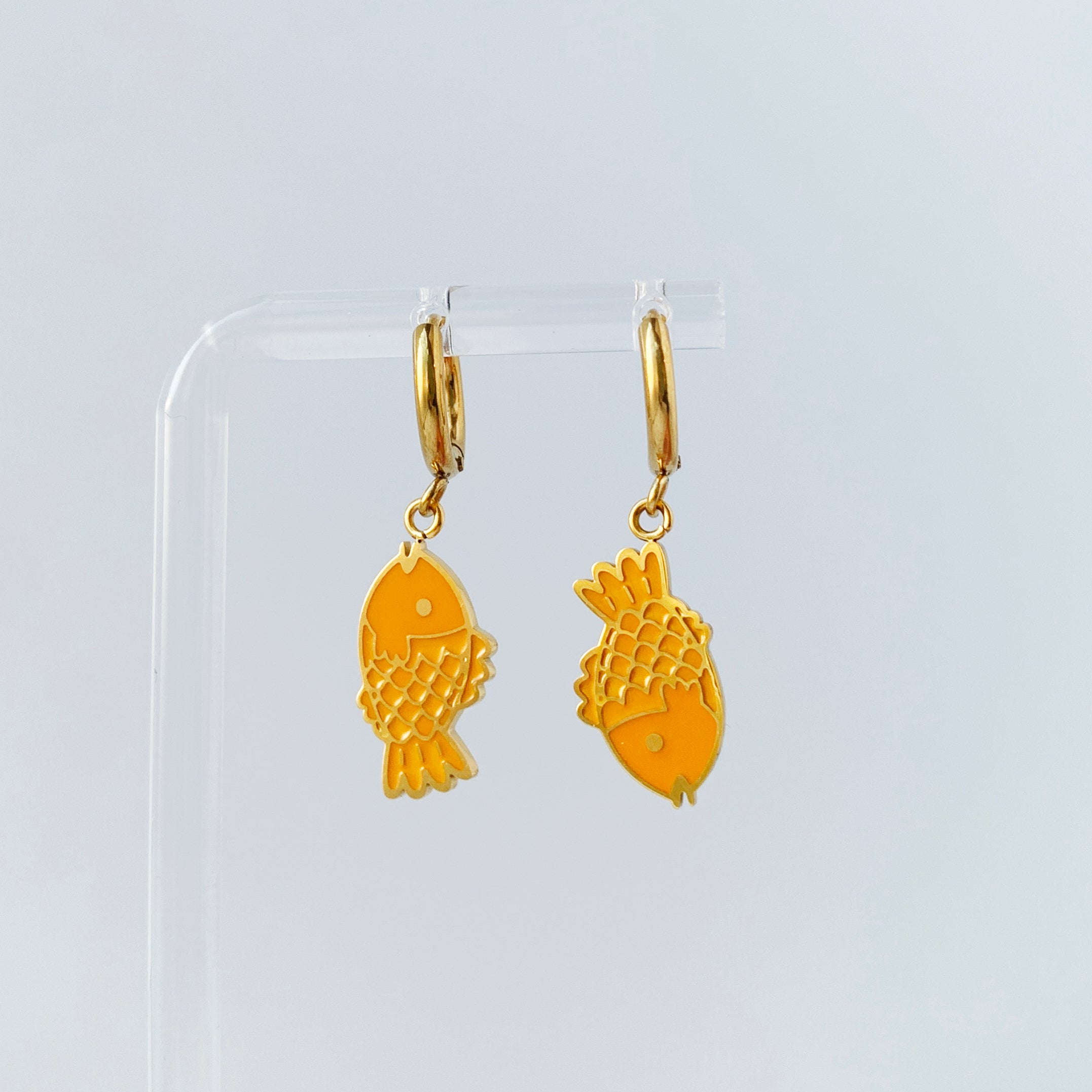 Small gold hoop earrings with charms of a taiyaki fish in opposing directions