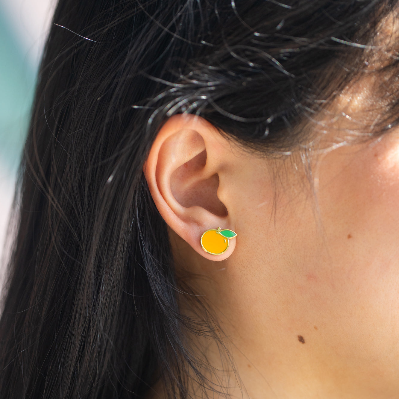 Close-up of person wearing orange stud earrings